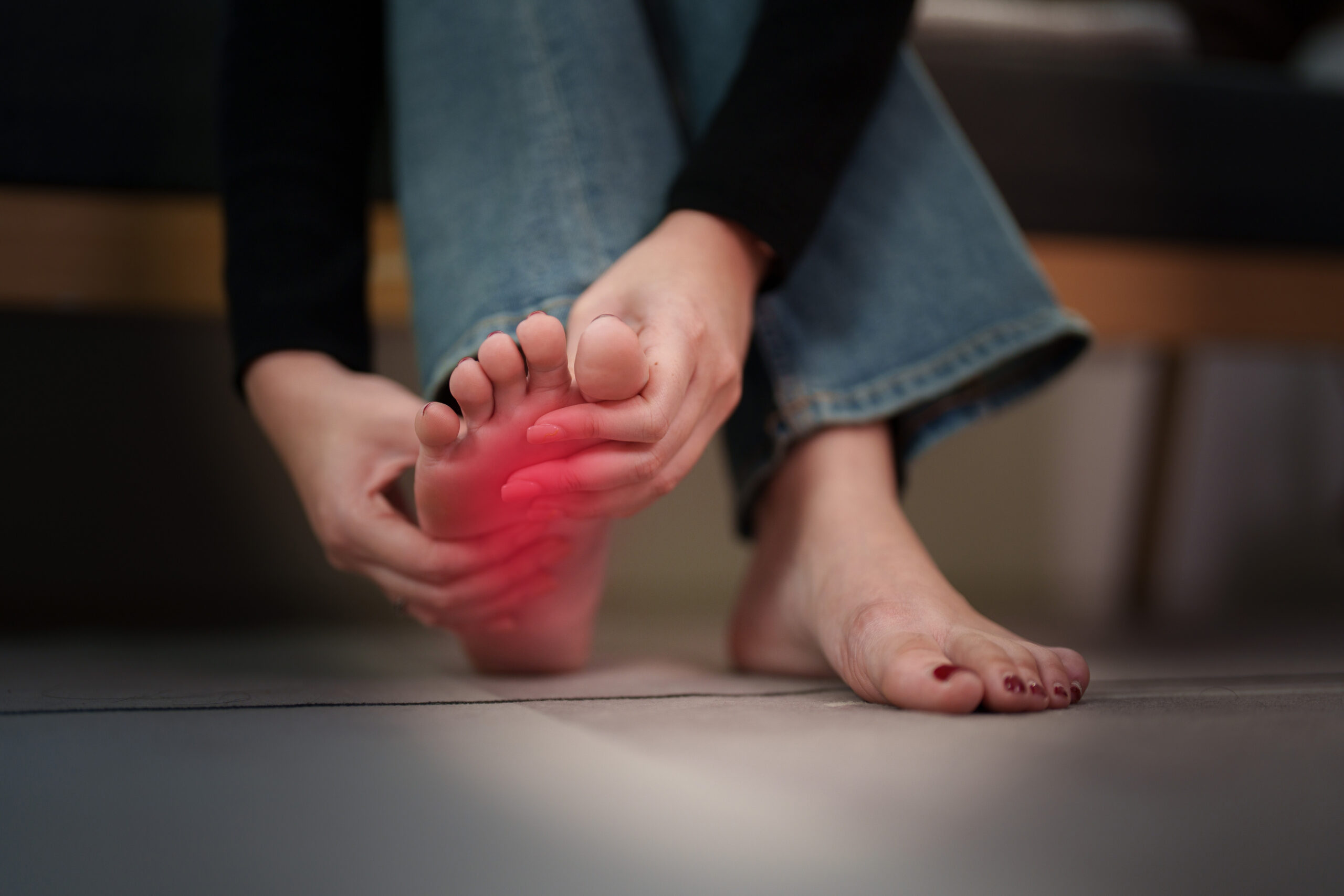 Person massaging painful foot at home for podiatry and pain relief